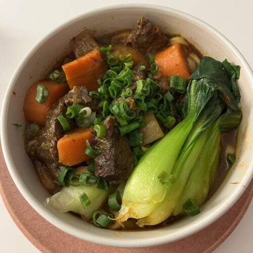 taiwanese beef noodle soup with carrots, daikon reddish and pok chioi in a bowl