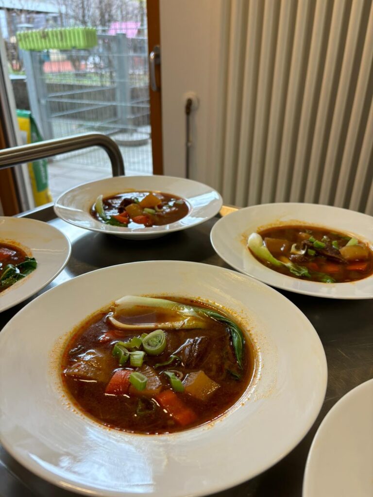 Taiwanese beef noodle soup in white bowls with tender braised beef, carrots, daikon reddish, and rich soy sauce base broth, garnished with green onions.