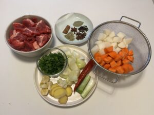 Bite-sized pieces of beef, radish and carrots. Aromatics cut into big chunks and a plate of chinese spices for broth
