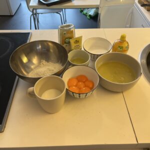 All the ingredients for castella cake prepared in separate bowls, including sugar, egg yolks, egg whites, sugar, oil, milk, flour,lemon juice, honey, and vanilla paste
