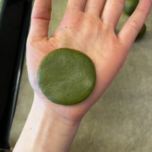 5-cm wide flat and round raw matcha cookie dough shaped on a palm for size reference