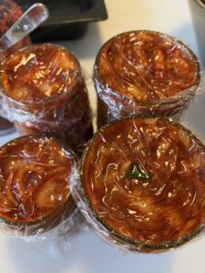 kimchi in jars with plastic wrop touching the surface of the kimchi