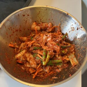 cabbage kimchi with daikon reddish, carrots, and sping onion in a bowl